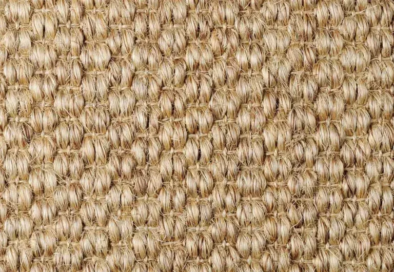 Close-up of a woven beige textured fabric or matting, featuring a repetitive pattern of tightly interwoven fibers.