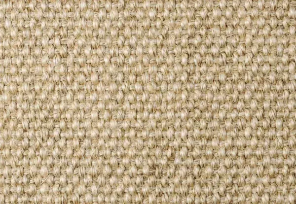 Close-up of a woven fabric with a coarse, natural texture in a beige color. The pattern is tightly knit, creating a uniform surface.
