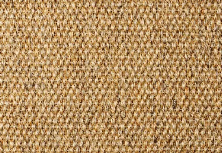 Close-up view of a woven, textured fabric in a beige color. The pattern consists of interlacing strands.