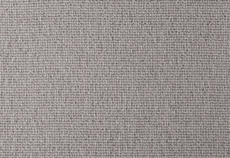 A close-up view of a textured, light grey, woven fabric with a uniform pattern.