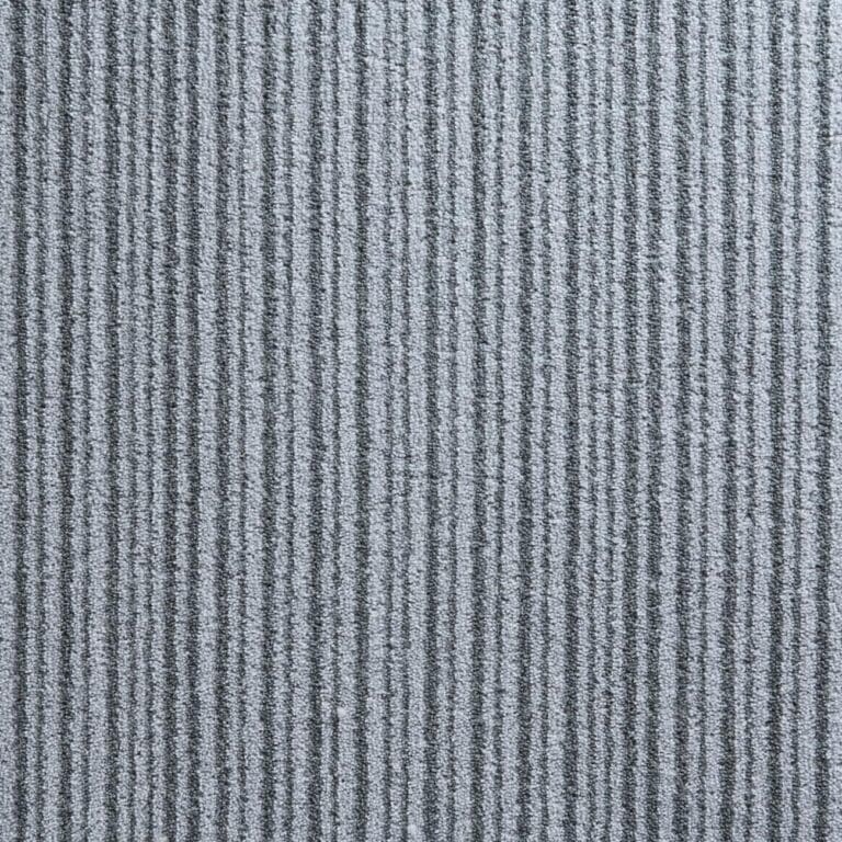 A close-up view of a gray carpet with vertical ridges creating a striped pattern.
