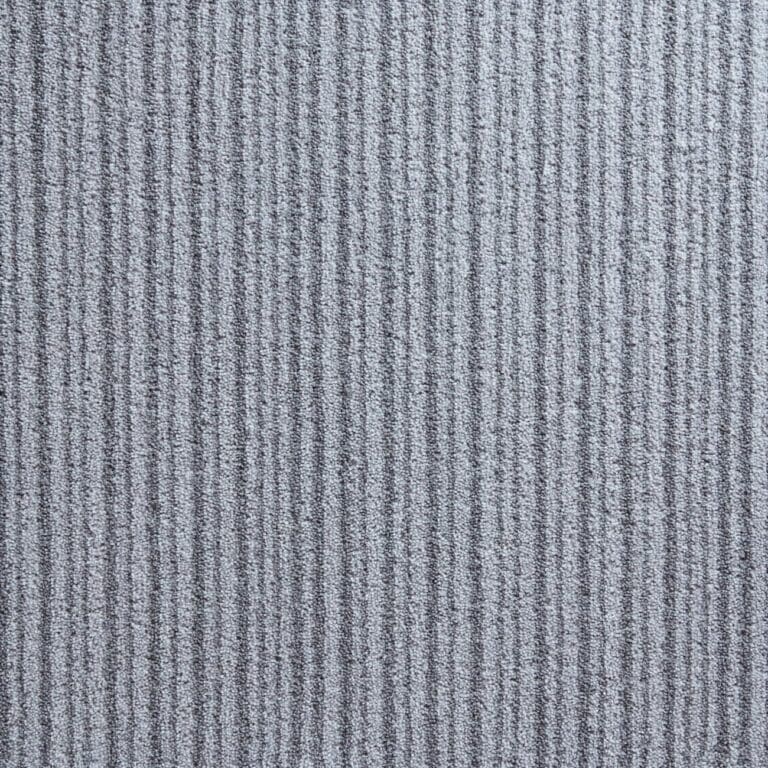 A close-up view of a textured, grey carpet with linear, vertical ridges.
