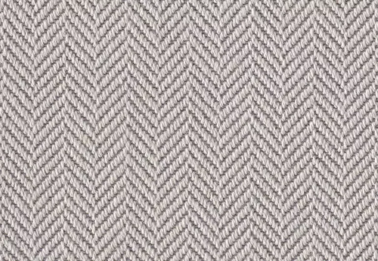 A close-up of a gray herringbone-patterned fabric with a repeating V-shaped weave design.