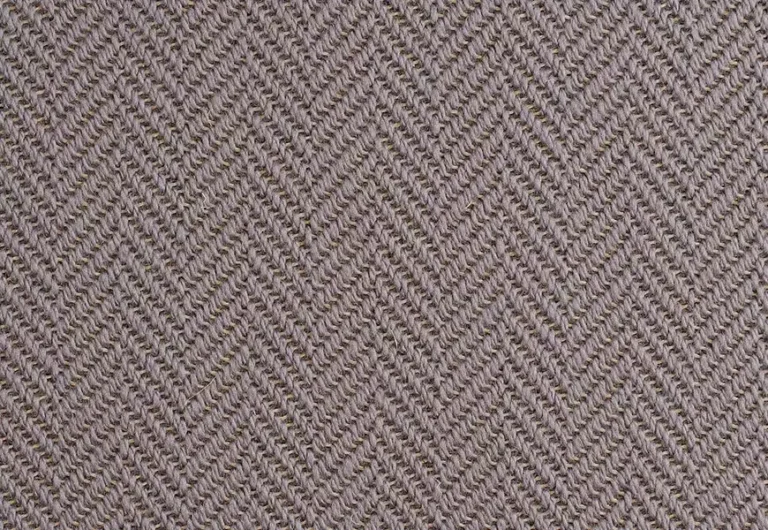 Close-up of a textured fabric with a chevron pattern in shades of beige and light brown. The fabric has a woven appearance.