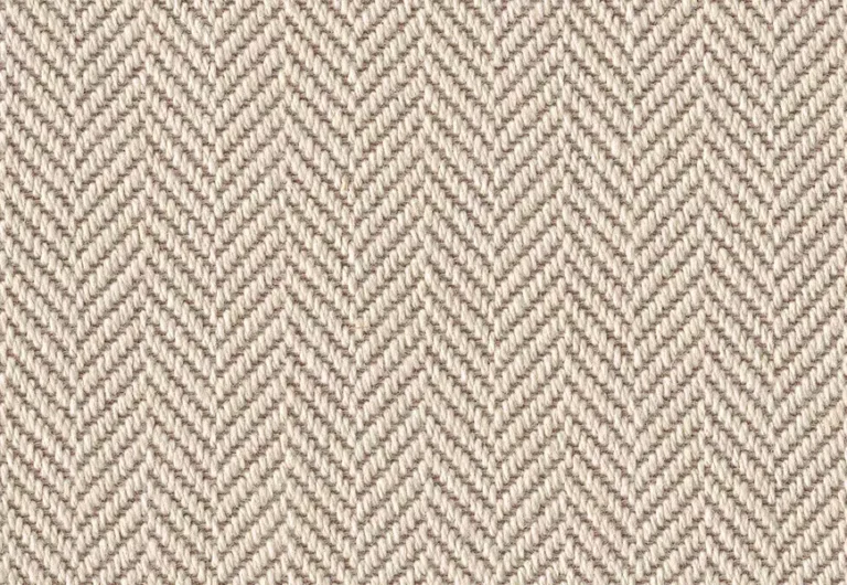 A beige herringbone patterned fabric with a repeating woven texture.