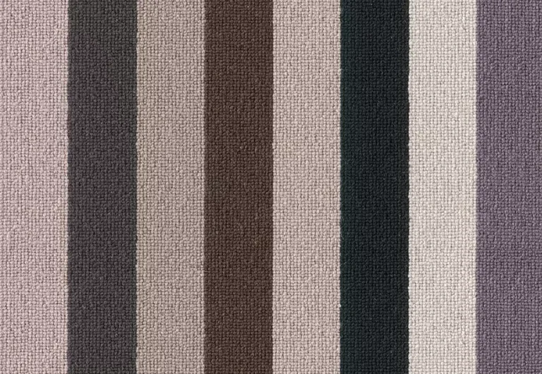A close-up view of a textured fabric with vertical stripes in various shades of gray, brown, and purple.