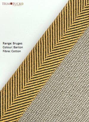 Close-up of a yellow and black patterned trim placed diagonally on a grey fabric. Text overlay reads: "Product Name: Bruges Binding, Colour: Barton, Fibre: Cotton".
