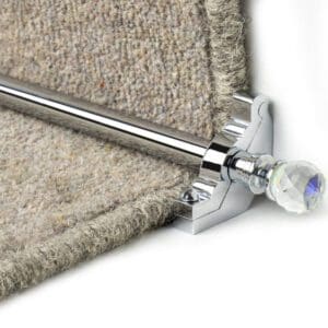 Close-up of a stair carpet secured by a chrome stair rod with a crystal finial on one end.