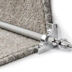 Close-up of a stair carpet holder featuring a silver finial end and a rod securing a gray carpet corner.