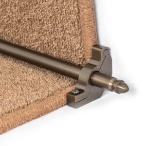 Close-up of a metal stair rod with a rounded finial, mounted on a carpeted staircase.