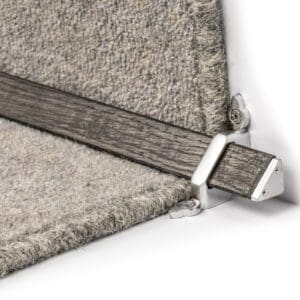 Close-up view of a metal and wood corner bracket securing two pieces of gray carpeted material.