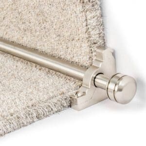 Close-up of a gray carpet stair runner held in place by a silver rod and bracket at the edge of a step.