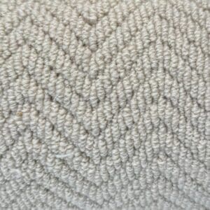 Close-up of a light grey fabric with a herringbone pattern. The surface has a soft, textured appearance with neatly arranged woven fibers, known as Wool Skein Herringbone Landes.