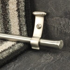 A metal stair rod bracket on a carpeted floor.