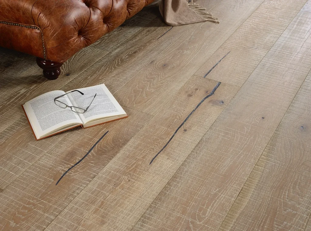 Open book and glasses on wooden floor.