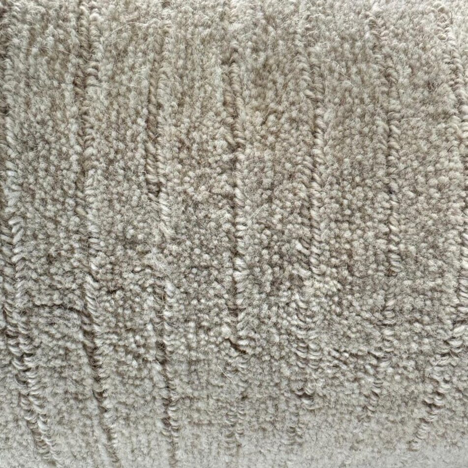Close-up of a textured beige Man Made Luxurious Carpet Remnant with visible horizontal and vertical stitching patterns.