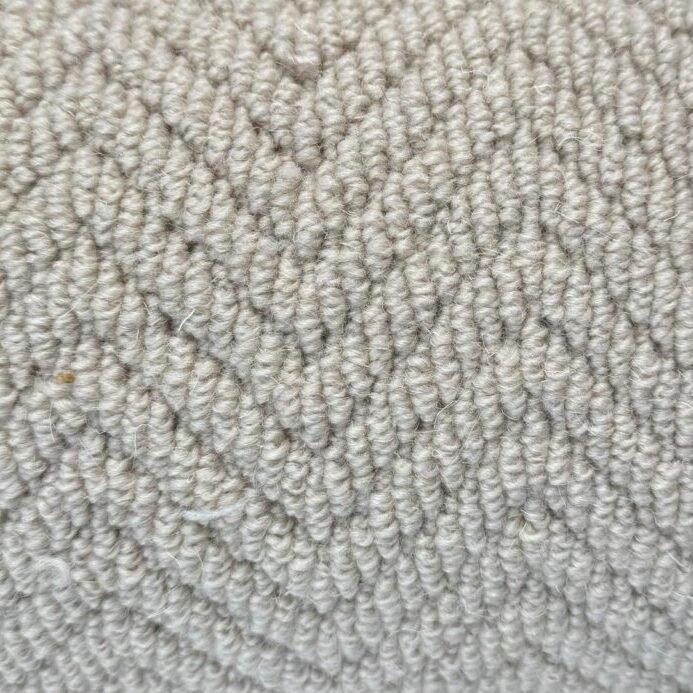 Close-up of a light grey fabric with a herringbone pattern. The surface has a soft, textured appearance with neatly arranged woven fibers, known as Wool Skein Herringbone Landes.